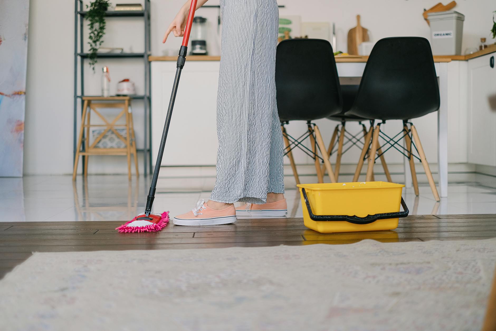 crop housewife cleaning wooden floor at home